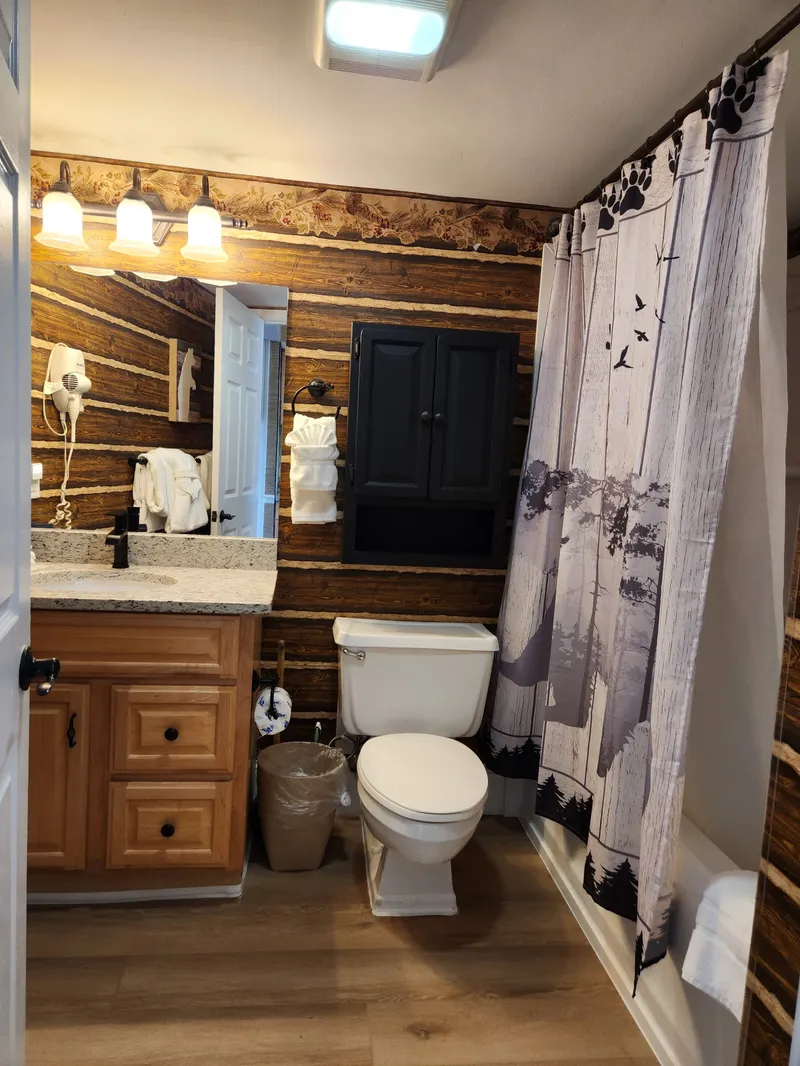 Step into your rustic bathroom featuring warm wood walls, granite counters, and charming cabin details that make every morning feel like a mountain retreat.