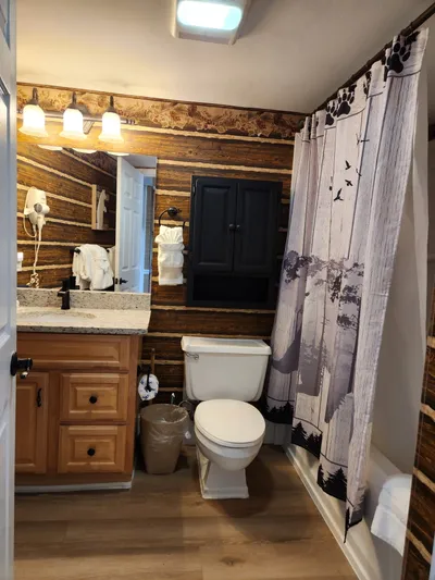 Step into your rustic bathroom featuring warm wood walls, granite counters, and charming cabin details that make every morning feel like a mountain retreat.