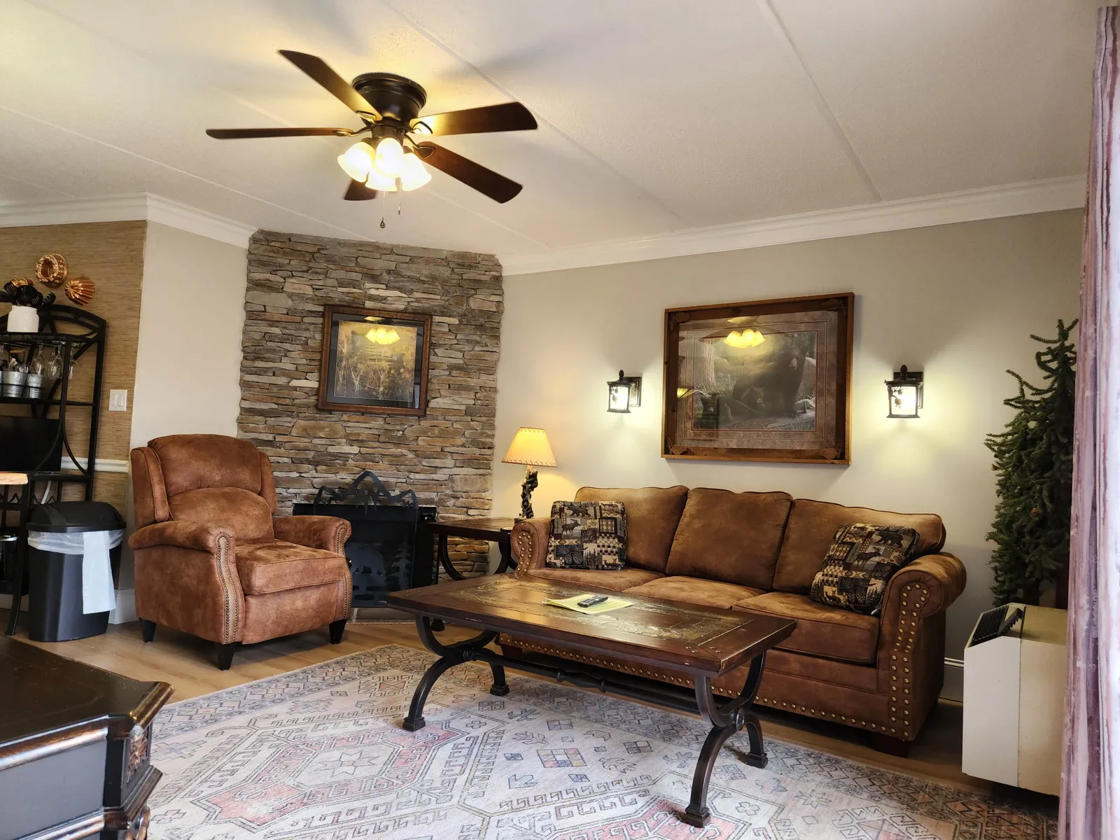 Relax in your cozy living room featuring rich leather furniture, rustic stone fireplace, and warm lighting for perfect evenings.