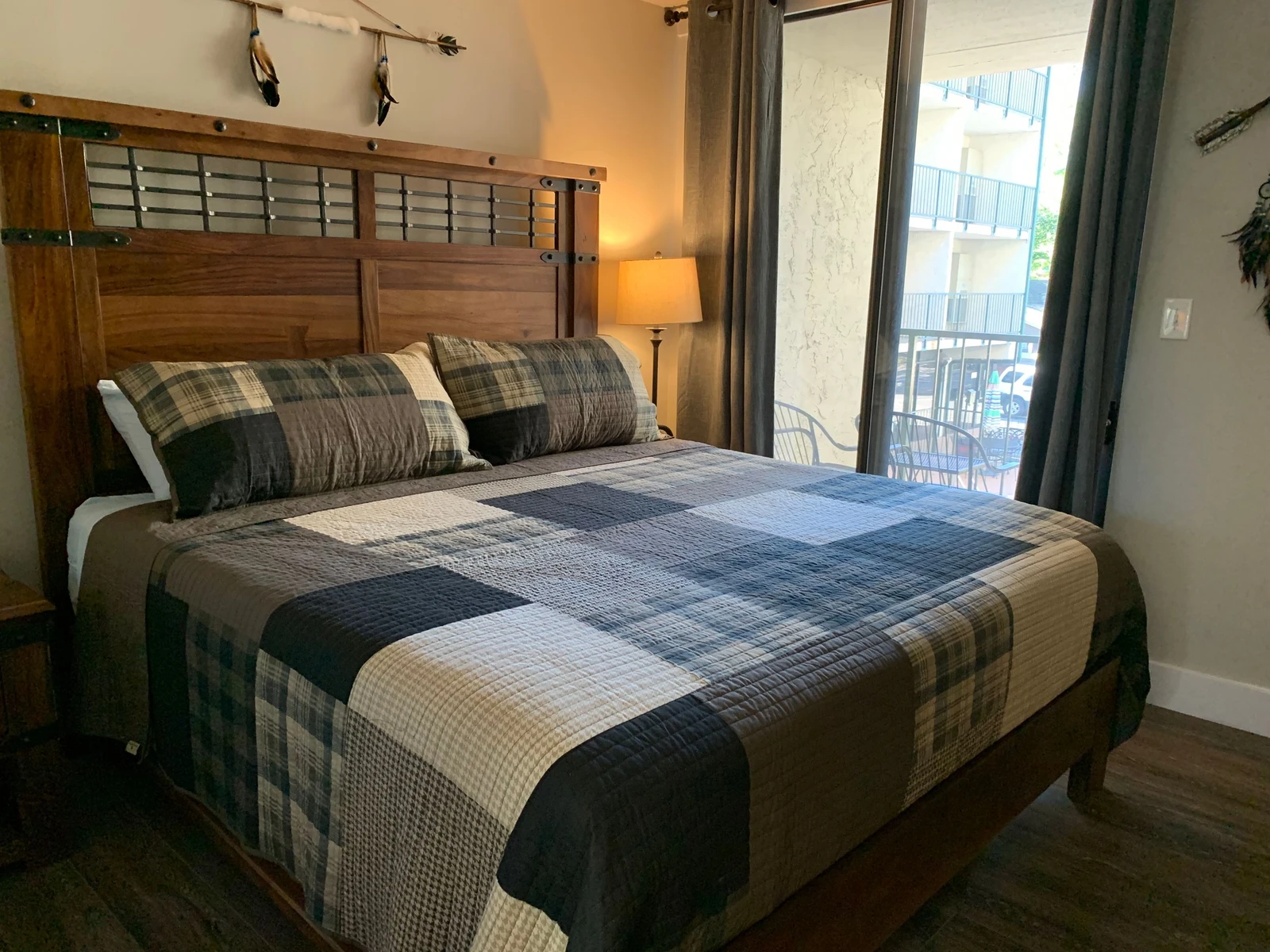 Rest peacefully on your comfortable bed with plaid quilted bedding, while natural light streams through the balcony doors.