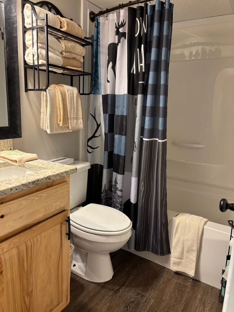 Step into your stylish bathroom with modern finishes—plush towels await, a glass-enclosed shower beckons, and rustic wood accents add warmth to your mountain retreat.
