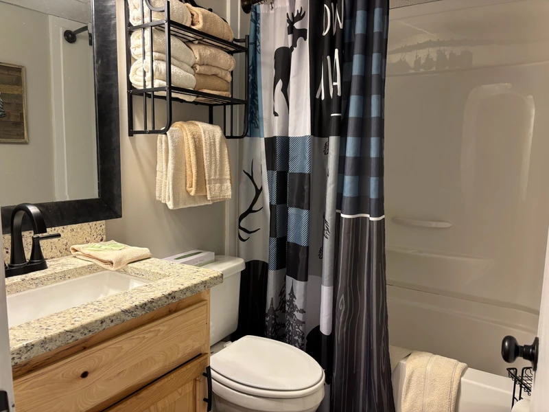 Step out of your outdoor adventures and into your private retreat. Fresh towels, thoughtful storage, and a nature-inspired touch make this spotless bathroom yours to enjoy.