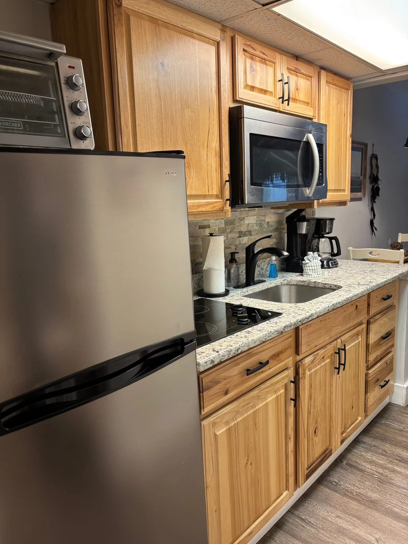 Your fully equipped kitchen features warm wood cabinetry, modern appliances including a cooktop and oven, and everything you need to prepare delicious meals during your stay.