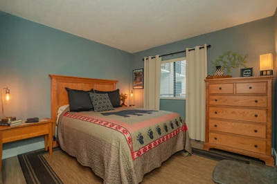 Your serene bedroom retreat features a cozy bed, warm wood furnishings, and calming blue-green walls that invite restful sleep after a day of adventure.