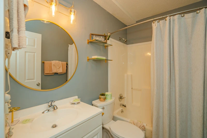 Step into your serene private bathroom, where calming blue-gray walls and soft lighting create a spa-like retreat. Fresh towels and thoughtful touches await your arrival.