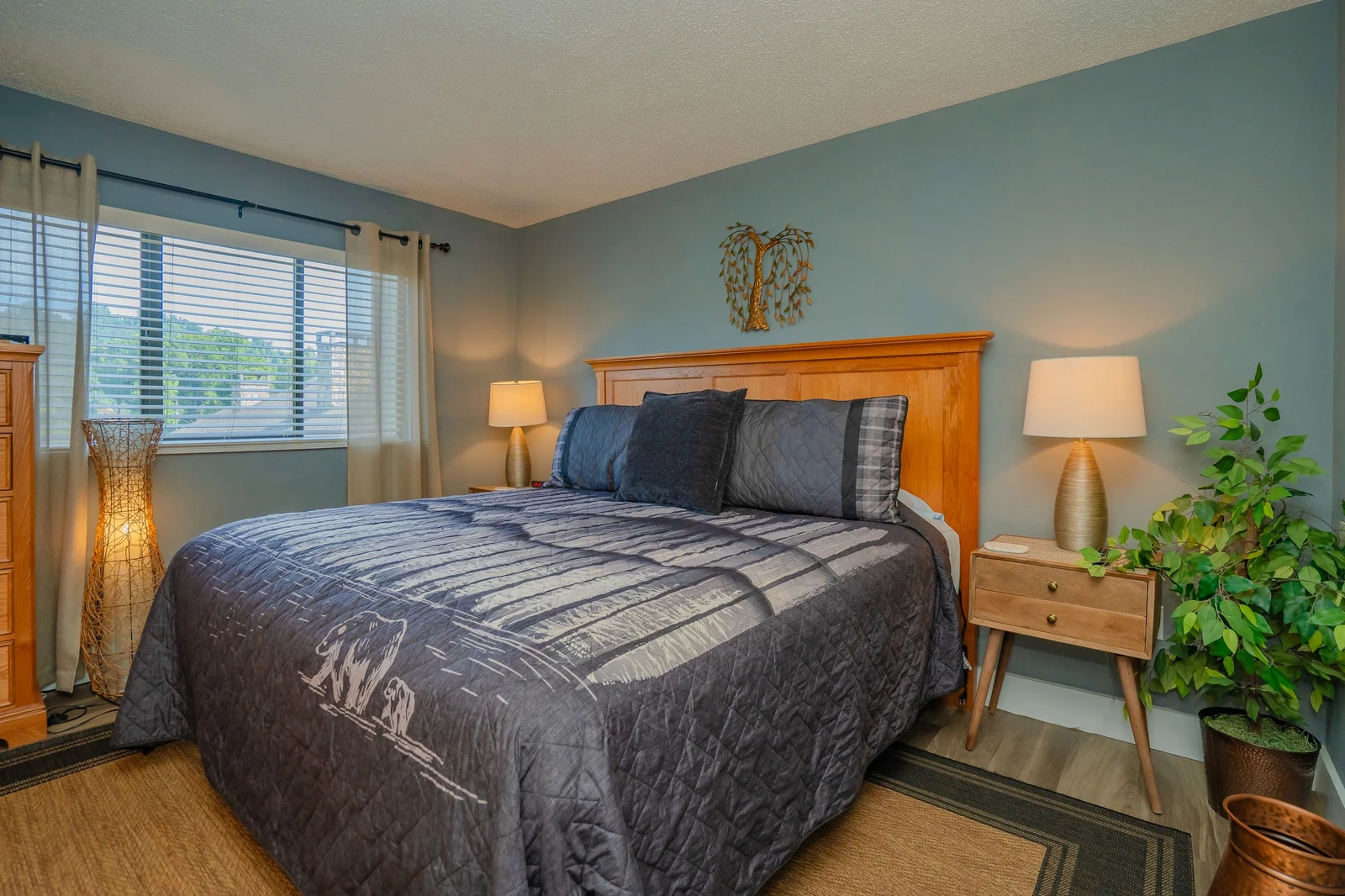 Sink into the soft quilted bedding in your serene bedroom, where warm lighting and calming blue-gray walls create a peaceful retreat after a day of adventure.