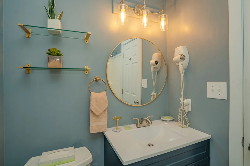 Step into your thoughtfully designed bathroom featuring calming blue tones, elegant gold accents, and modern amenities including dual hair dryers for your convenience.
