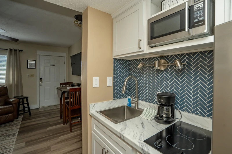 Your fully equipped kitchenette features modern appliances, elegant herringbone tile backsplash, and everything you need to prepare light meals during your stay.
