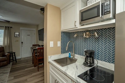Your fully equipped kitchenette features modern appliances, elegant herringbone tile backsplash, and everything you need to prepare light meals during your stay.