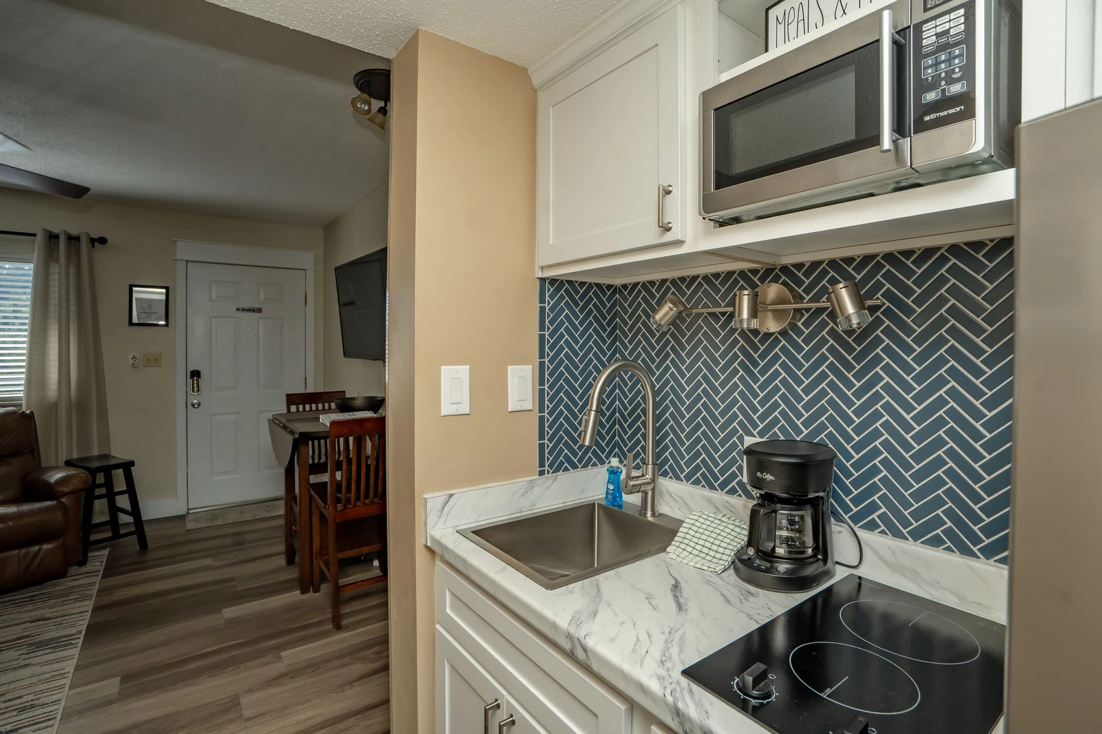 Your fully equipped kitchenette features modern appliances, elegant herringbone tile backsplash, and everything you need to prepare light meals during your stay.