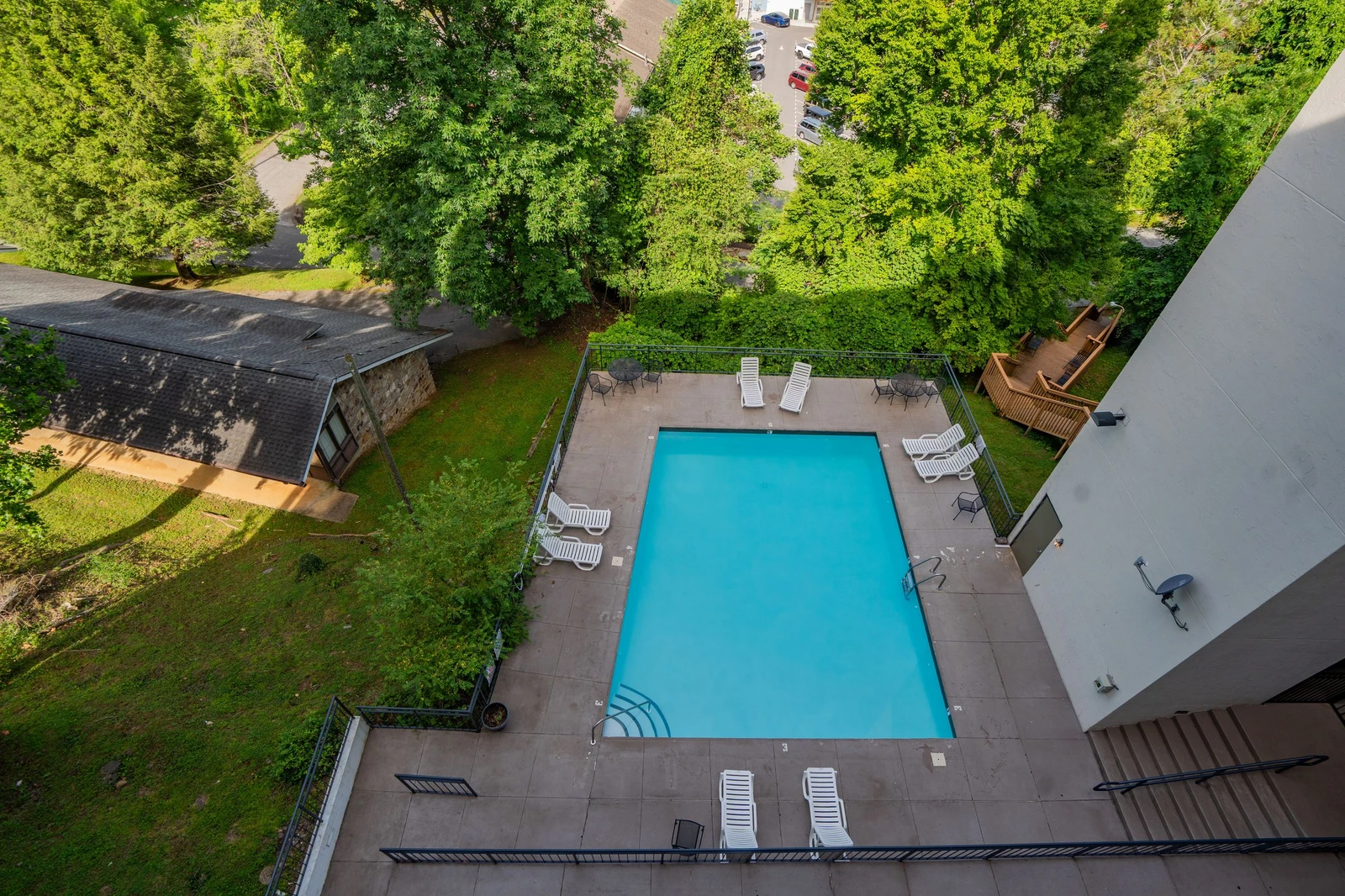 Aerial view of the property's outdoor pool area, surrounded by natural greenery and accessible from the main building, with lounge seating on the deck.