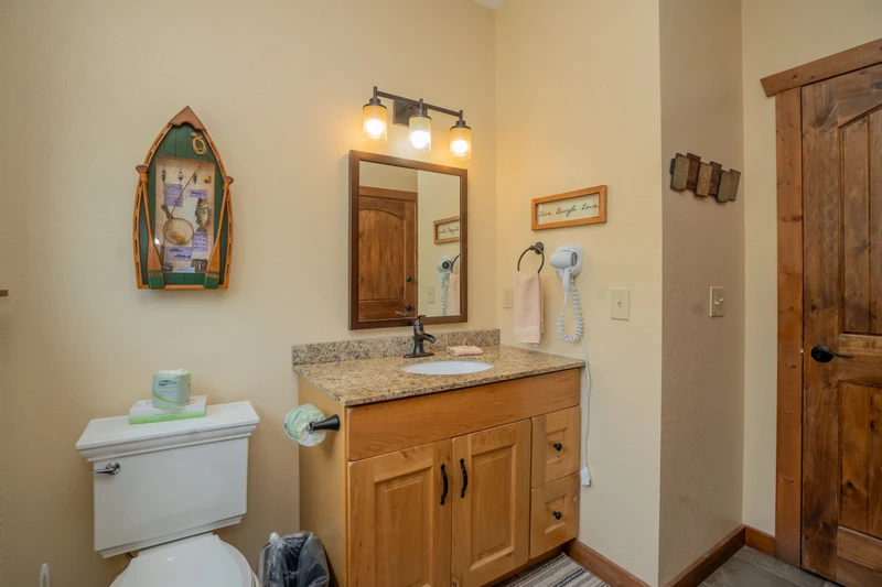 Your bathroom blends coastal charm and comfort—notice the boat-shaped shelf adding a playful touch above the granite vanity. Everything's ready for you, from fresh towels to the hairdryer by the sink.