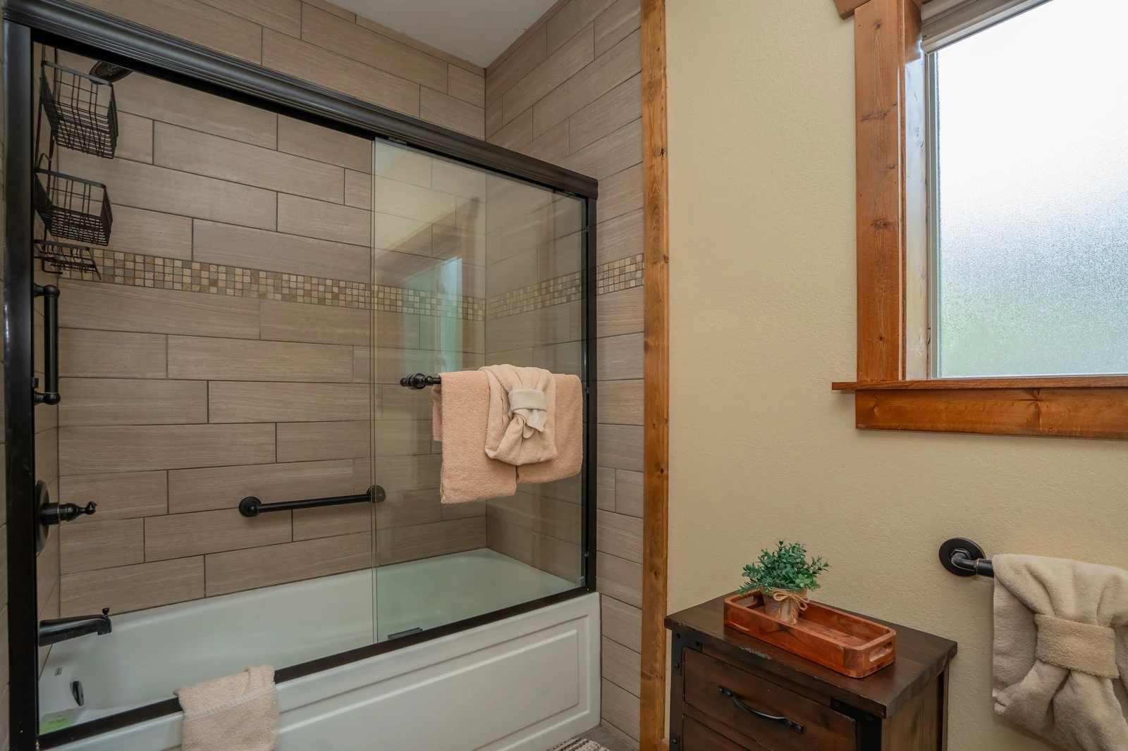 Relax in your own stylish bathroom with a spacious tub-shower combo, warm wood accents, and natural light. Fresh towels are ready for your arrival.