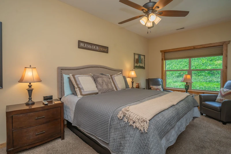 Unwind in your inviting bedroom, where soft linens and gentle lamplight create the perfect sanctuary for restful nights. The window frames lush greenery, letting you wake to nature's peaceful embrace.