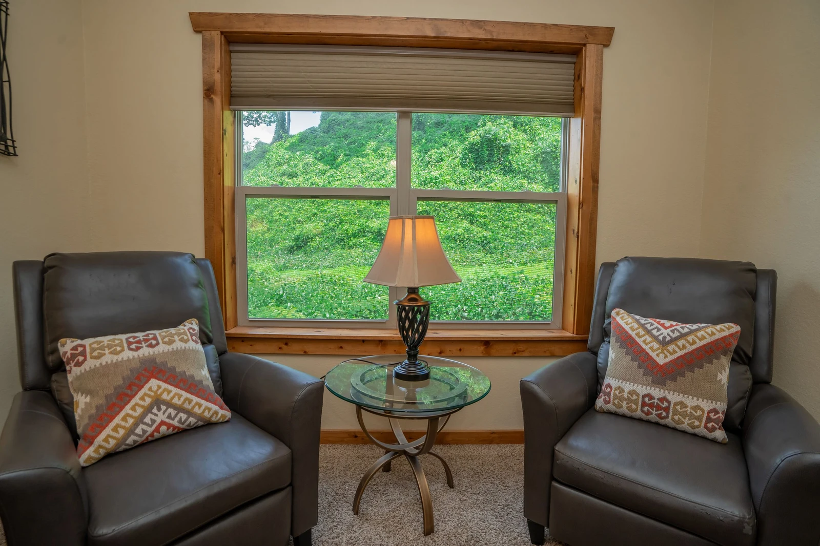 Settle into your private reading nook, where two plush leather chairs invite you to relax by the window. Gaze out at the lush mountain scenery framing your peaceful retreat—perfect for morning coffee or winding down with a book.