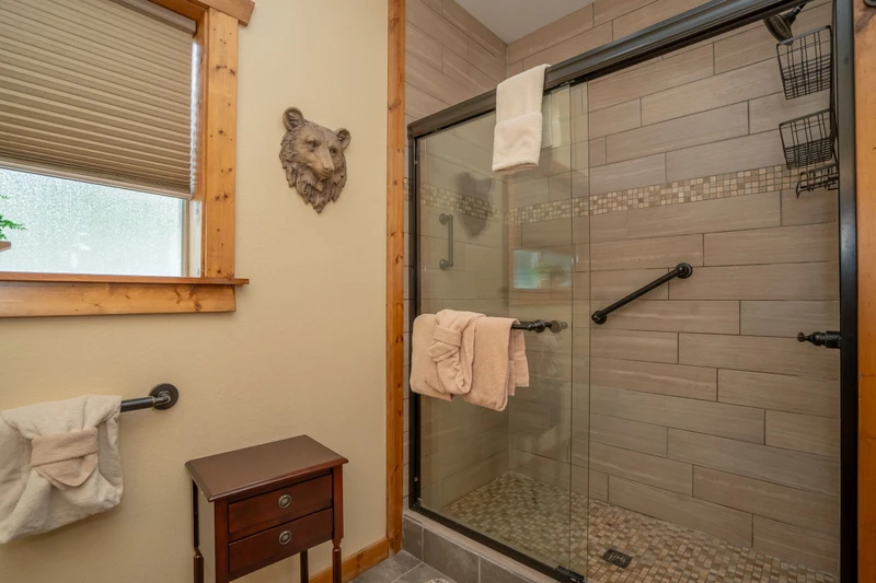 Step into your private spa-like retreat with a spacious walk-in shower, warm wood accents, and plush towels waiting for you after a day of mountain adventure.
