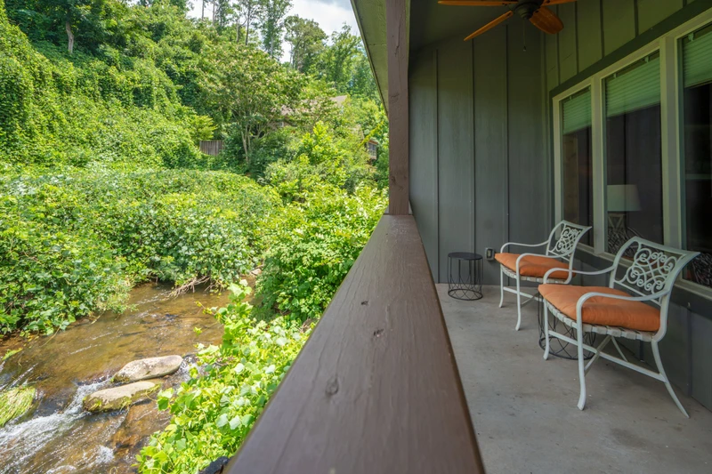 Relax on your private balcony overlooking a gentle stream flowing through lush greenery—your peaceful retreat with nature at your doorstep.