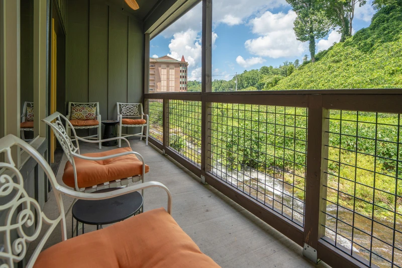 Your private screened balcony offers cushioned seating where you can relax with morning coffee while taking in views of the lush hillside and seasonal creek below.