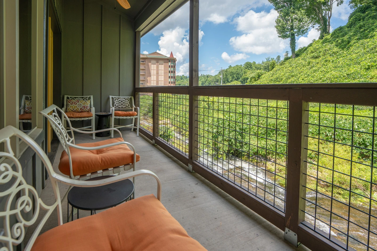 Your private screened balcony offers cushioned seating where you can relax with morning coffee while taking in views of the lush hillside and seasonal creek below.