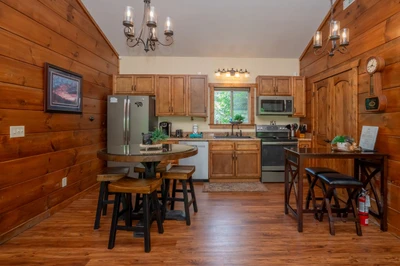 Step into your cozy cabin-style kitchen, where warm wood walls and natural light invite you to brew morning coffee and gather around the rustic table for meals with loved ones.