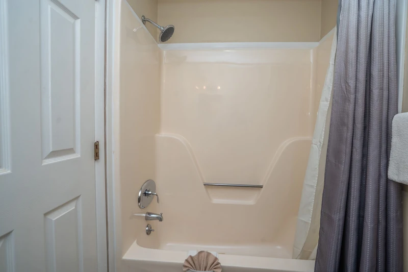 Step into your private sanctuary with a pristine tub-shower combo featuring a rain-style showerhead and sleek chrome fixtures. The built-in shelf keeps your essentials organized and within reach.