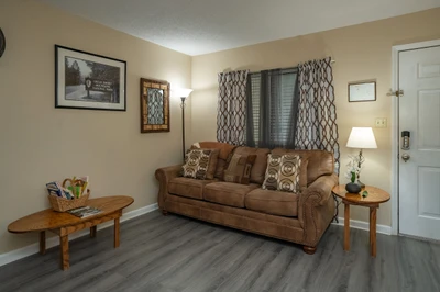 Settle into your cozy living room, where a plush sofa and warm lighting invite you to unwind after a day of exploring. The comfortable seating area offers a perfect spot to relax and plan your next adventure.