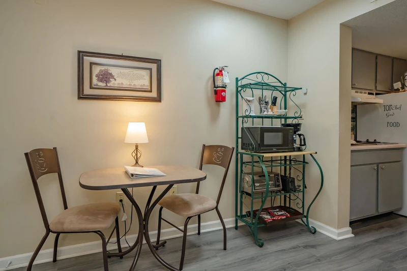 Your cozy dining nook invites you to enjoy morning coffee or a casual meal at the intimate café-style table. A teal shelving unit holds snacks and a microwave for your convenience.
