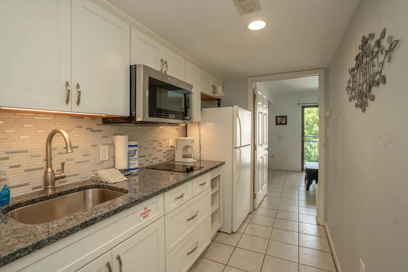 Step into your fully equipped galley kitchen with granite counters, modern appliances, and ample storage, all flowing seamlessly toward your private entrance and outdoor escape.