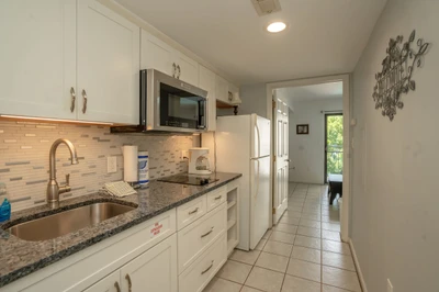 Step into your fully equipped galley kitchen with granite counters, modern appliances, and ample storage, all flowing seamlessly toward your private entrance and outdoor escape.