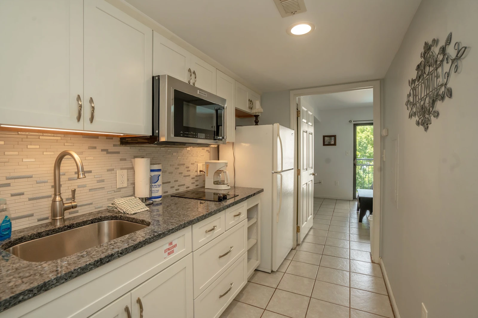 Step into your fully equipped galley kitchen with granite counters, modern appliances, and ample storage, all flowing seamlessly toward your private entrance and outdoor escape.