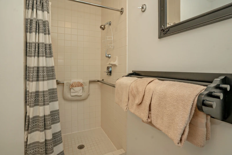 Your bathroom features a convenient walk-in shower with fresh towels ready for you. The thoughtfully designed space includes grab bars for added safety and comfort during your stay.