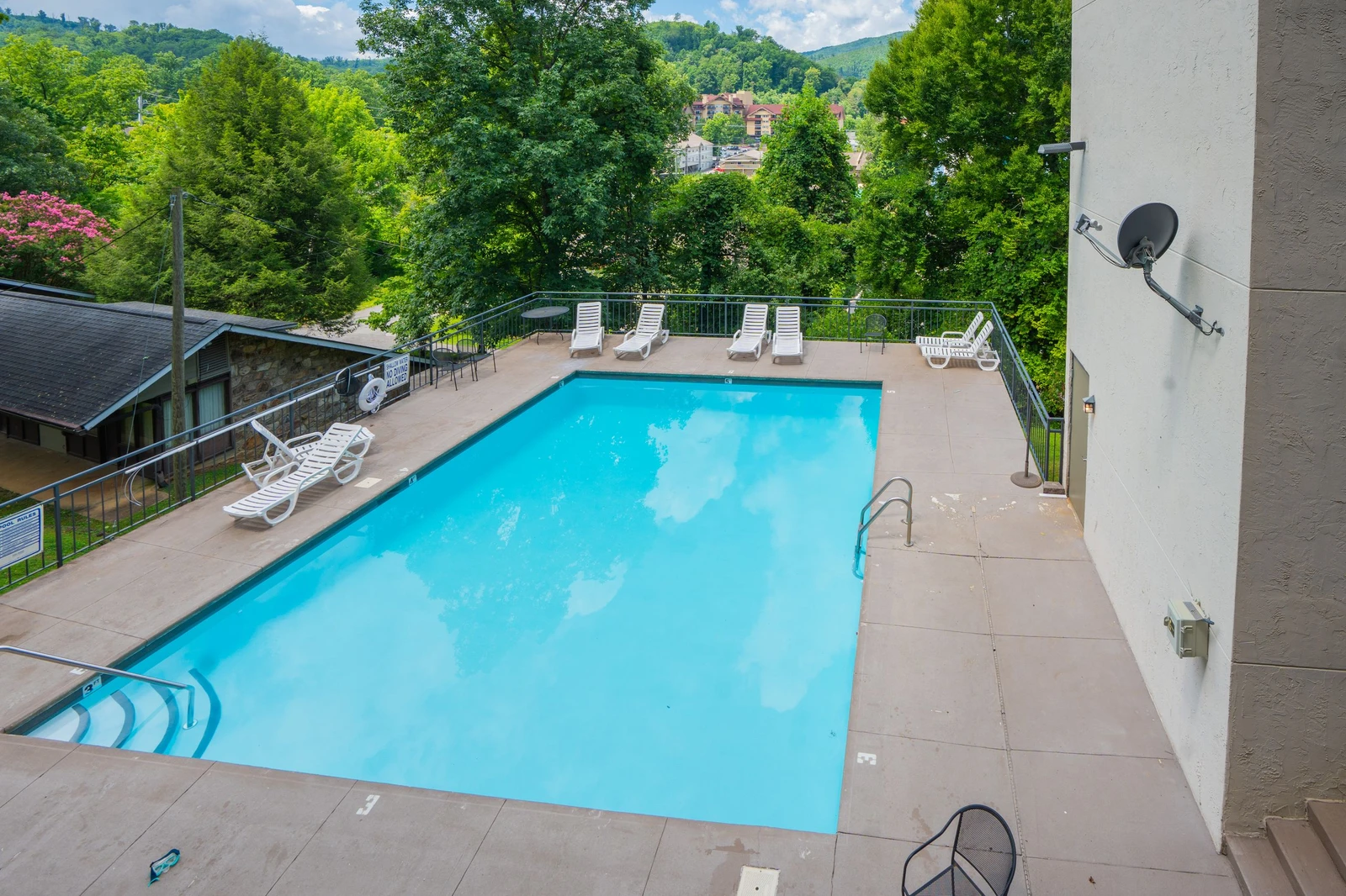 A sparkling pool surrounded by lush trees and mountain views, nestled in a scenic hillside setting. The peaceful surroundings and refreshing water create an ideal retreat.