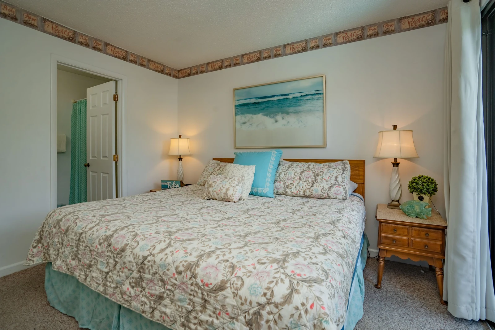 Sink into a plush bed dressed in soft, coastal-inspired linens. Warm lamps flanking each side create a cozy glow while you unwind in your serene retreat.