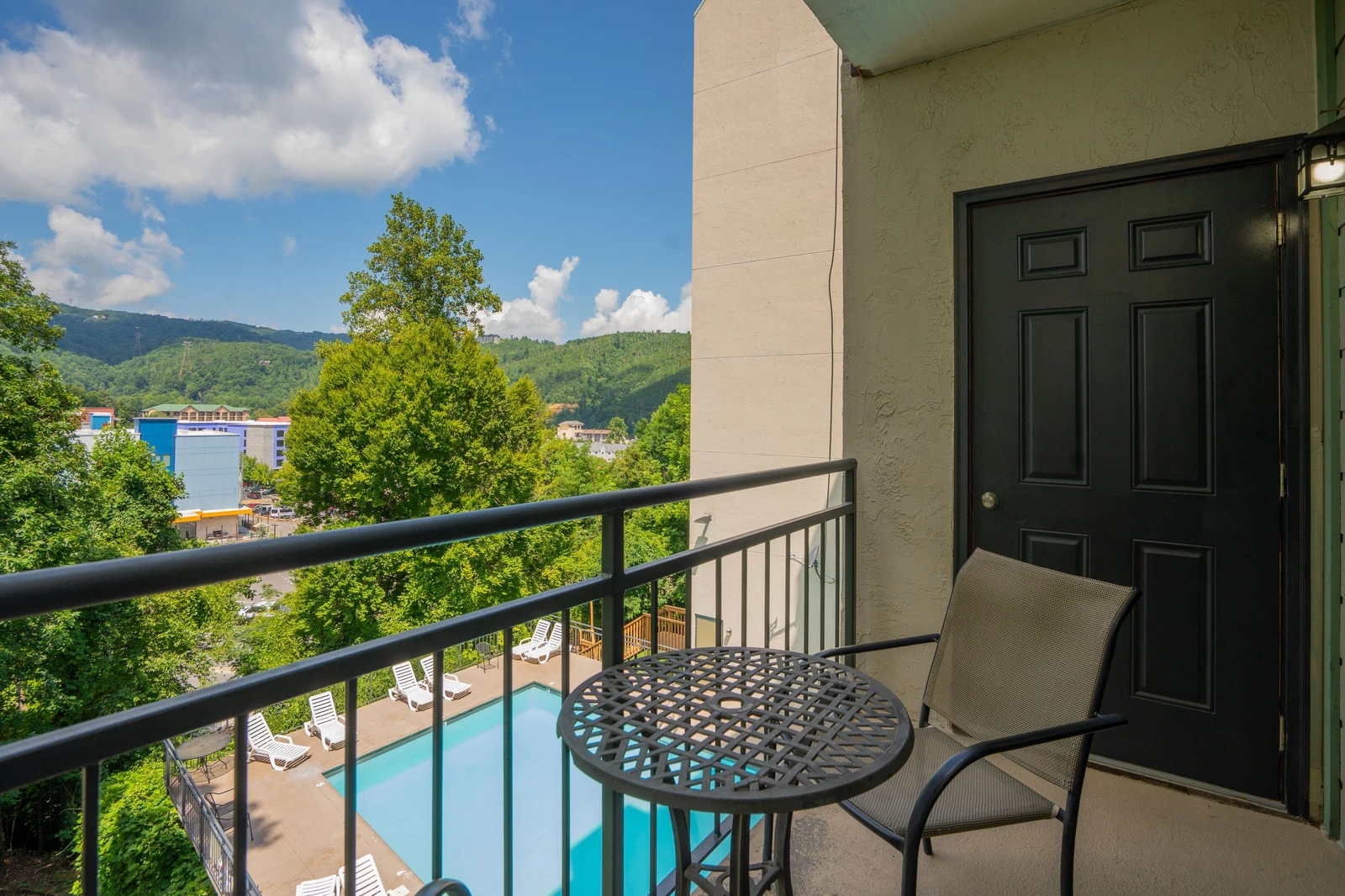 Step onto your private balcony and soak in sweeping mountain views framed by lush greenery. A cozy bistro table awaits for morning coffee while you overlook the sparkling pool below.