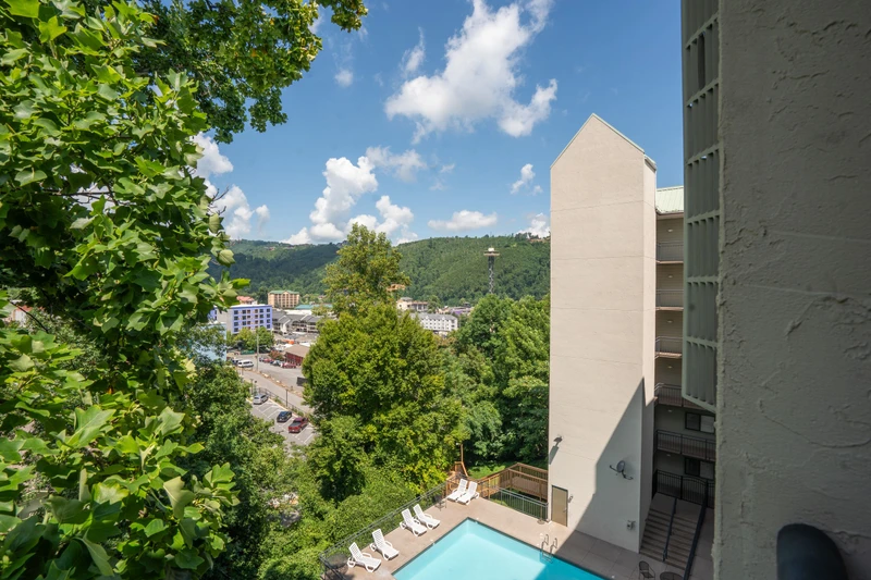 The property sits nestled among lush green hillsides and mountain terrain, with a private pool and sun loungers tucked into the landscape below. A peaceful, scenic setting perfect for a mountain getaway.