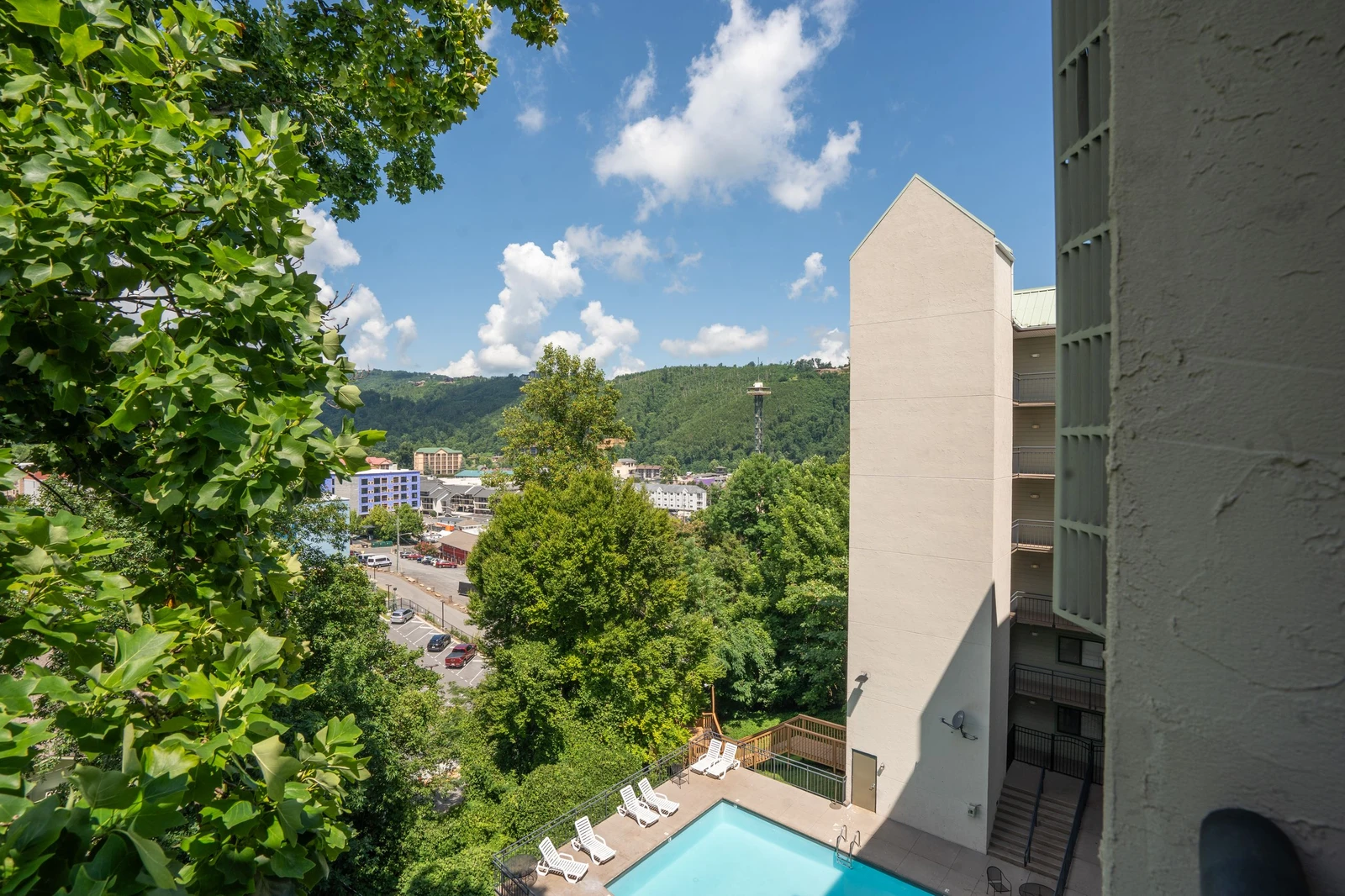 The property sits nestled among lush green hillsides and mountain terrain, with a private pool and sun loungers tucked into the landscape below. A peaceful, scenic setting perfect for a mountain getaway.