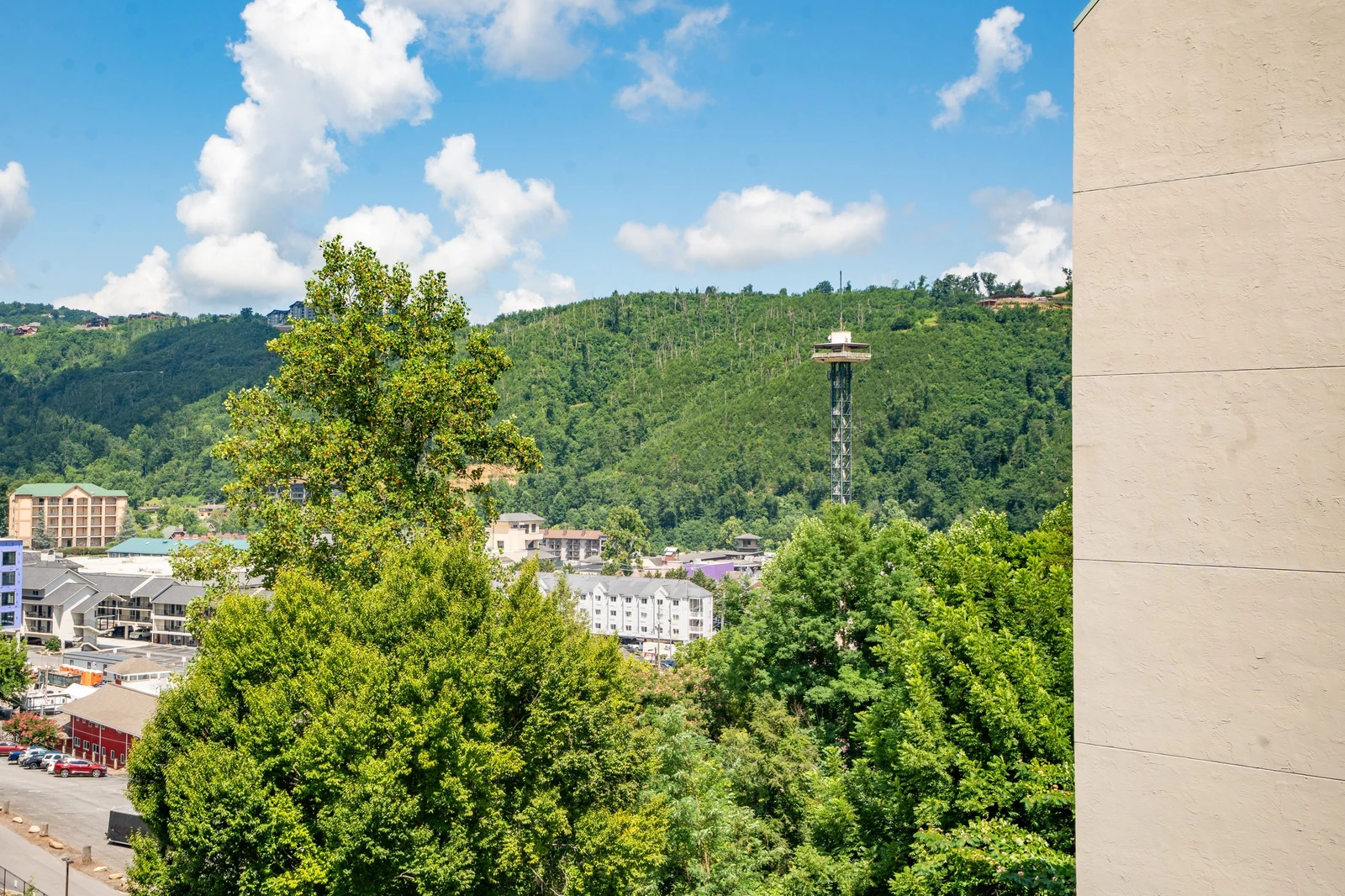 The property sits near downtown Gatlinburg with the iconic Space Needle visible among lush tree-covered hills, offering easy access to local attractions and entertainment.
