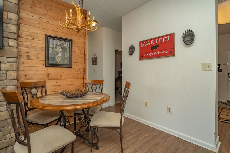 Gather around the rustic dining table under the warm glow of an antler chandelier, where charming bear-themed touches and natural wood accents make every meal feel like a mountain retreat.