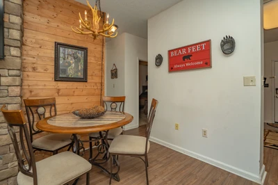 Gather around the rustic dining table under the warm glow of an antler chandelier, where charming bear-themed touches and natural wood accents make every meal feel like a mountain retreat.