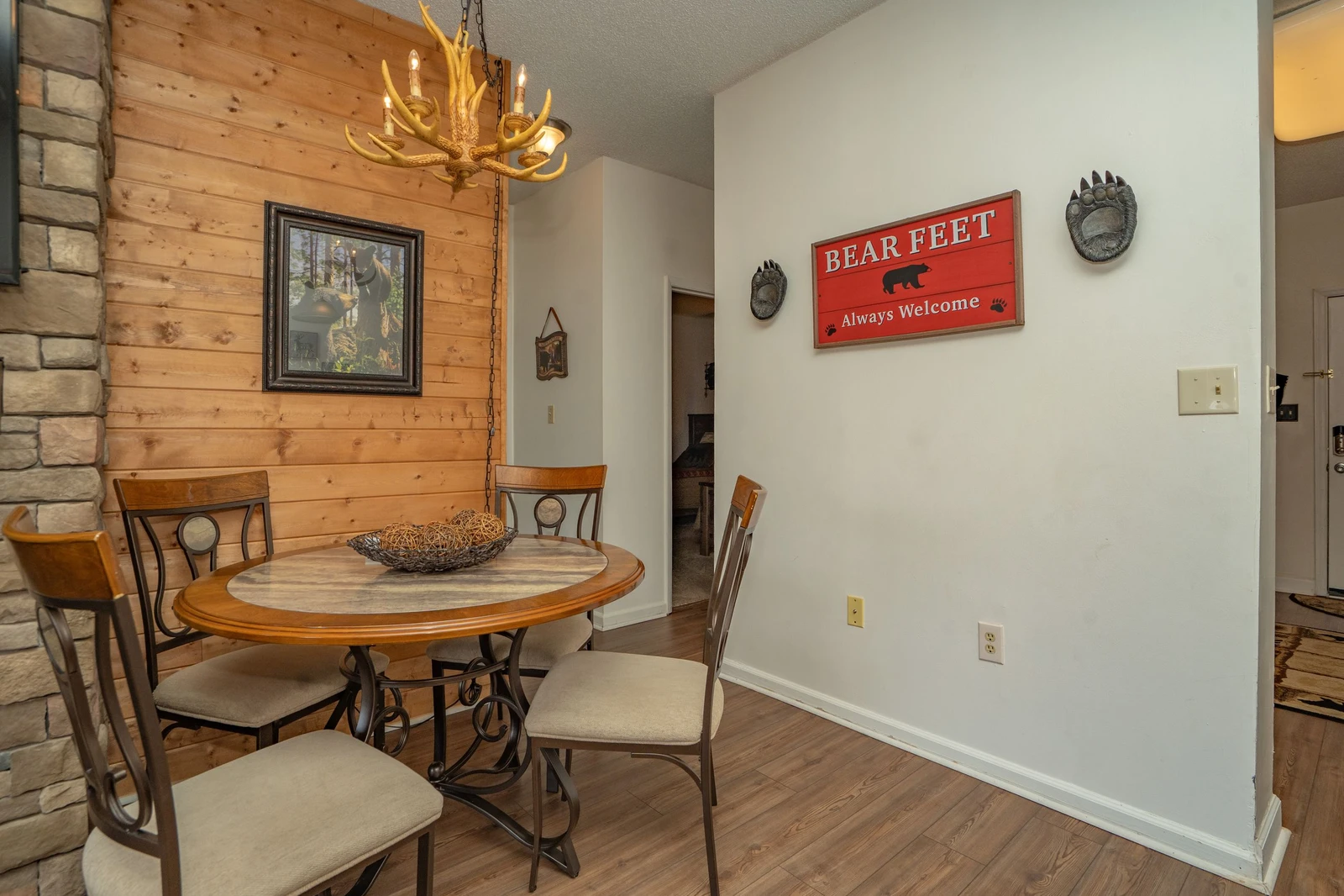 Gather around the rustic dining table under the warm glow of an antler chandelier, where charming bear-themed touches and natural wood accents make every meal feel like a mountain retreat.