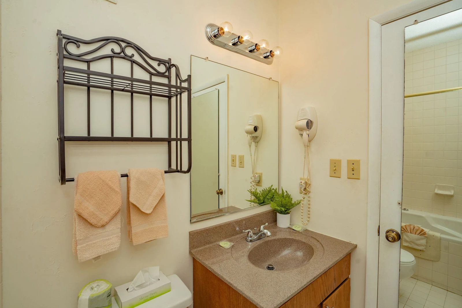 Freshen up in your private bathroom with soft towels, a vanity mirror, and thoughtful touches like greenery and a hairdryer for your convenience.
