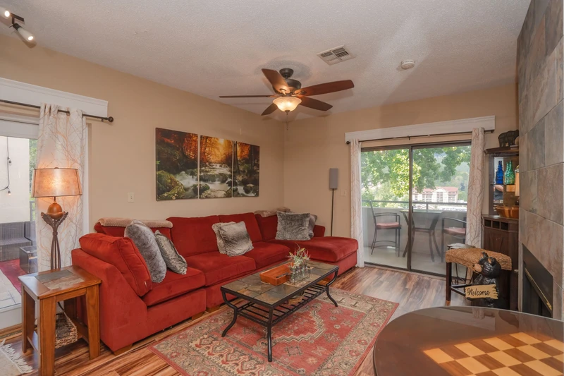 Unwind in your inviting living space featuring warm wood-style flooring, a plush sectional sofa, and a cozy fireplace—perfect for relaxing after a day of exploring nearby attractions.