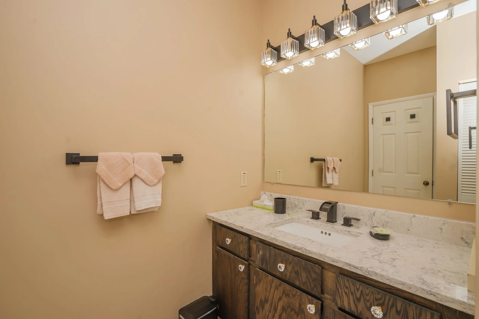 Step into your serene bathroom retreat with marble counters, warm wood cabinetry, and plush pink towels ready for your stay.