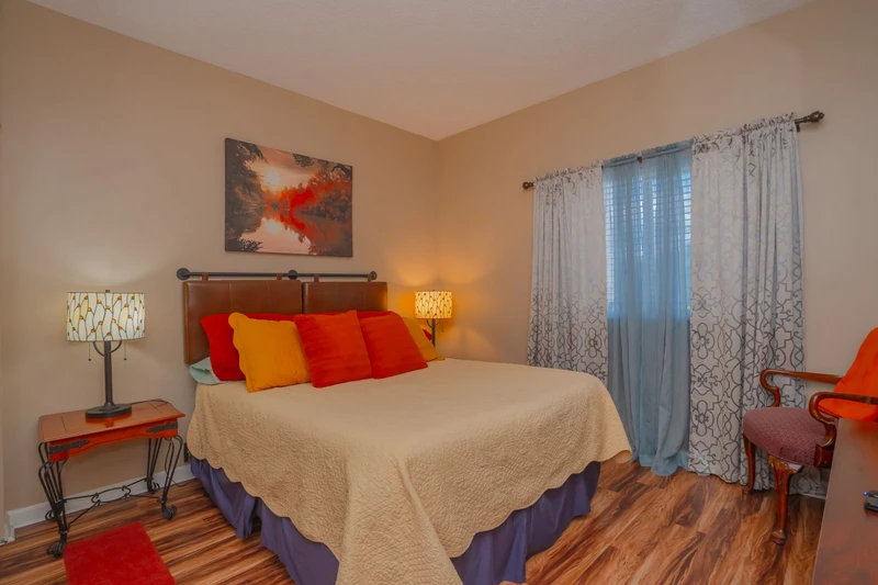 Sink into plush bedding with vibrant throw pillows that add warmth and personality. Natural light filters through sheer curtains, creating a peaceful retreat for your stay.