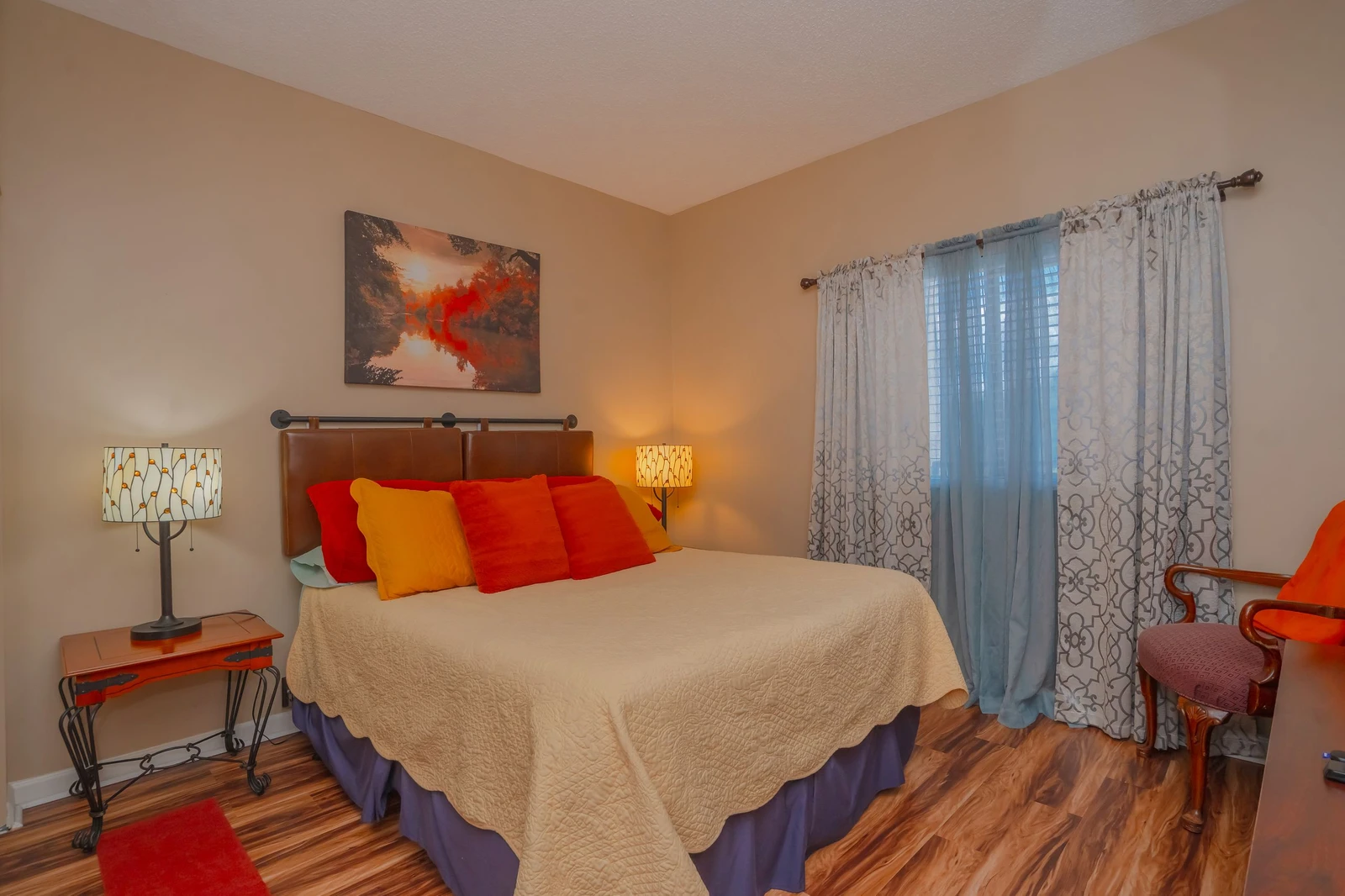 Sink into plush bedding with vibrant throw pillows that add warmth and personality. Natural light filters through sheer curtains, creating a peaceful retreat for your stay.