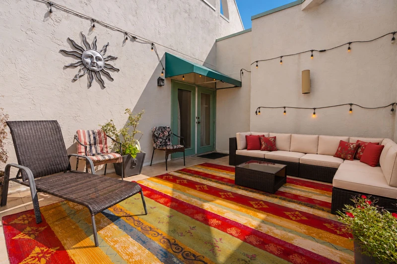 Step into your private courtyard oasis, where warm string lights and plush outdoor seating invite you to unwind under the desert sky. A cheerful sun sculpture and vibrant textiles set the tone for relaxed evenings.
