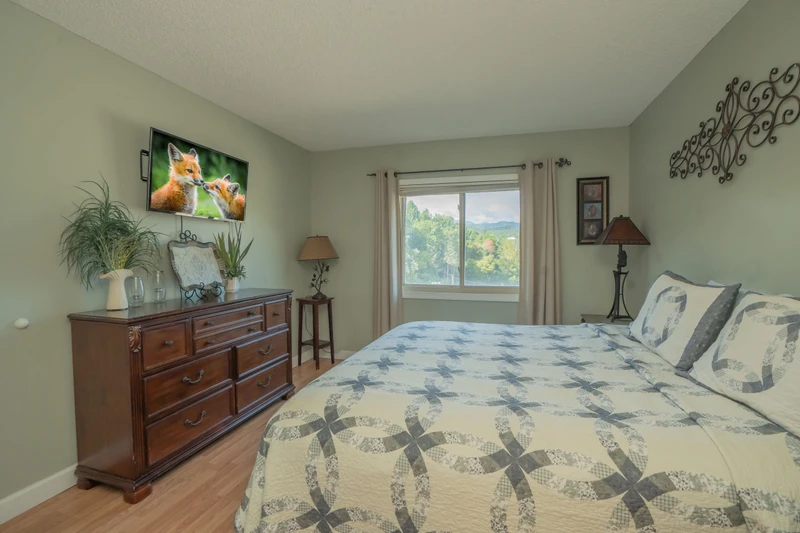 Wake up to mountain and forest views in this peaceful bedroom, complete with a cozy quilted bed and warm wood furnishings.