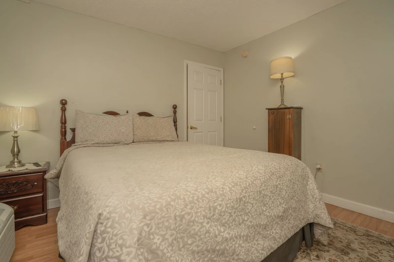 Slip into this serene bedroom with its elegant wood-carved bed and soft linens. You'll appreciate the classic charm and peaceful ambiance perfect for restful nights.