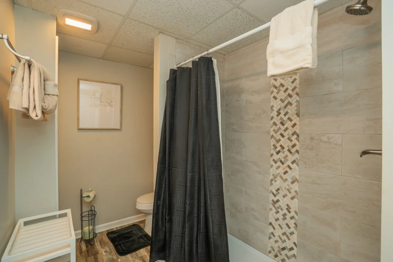 Step out of your shower onto soft towels after rinsing off under the rainfall showerhead, surrounded by elegant tile work and modern fixtures designed for your comfort.