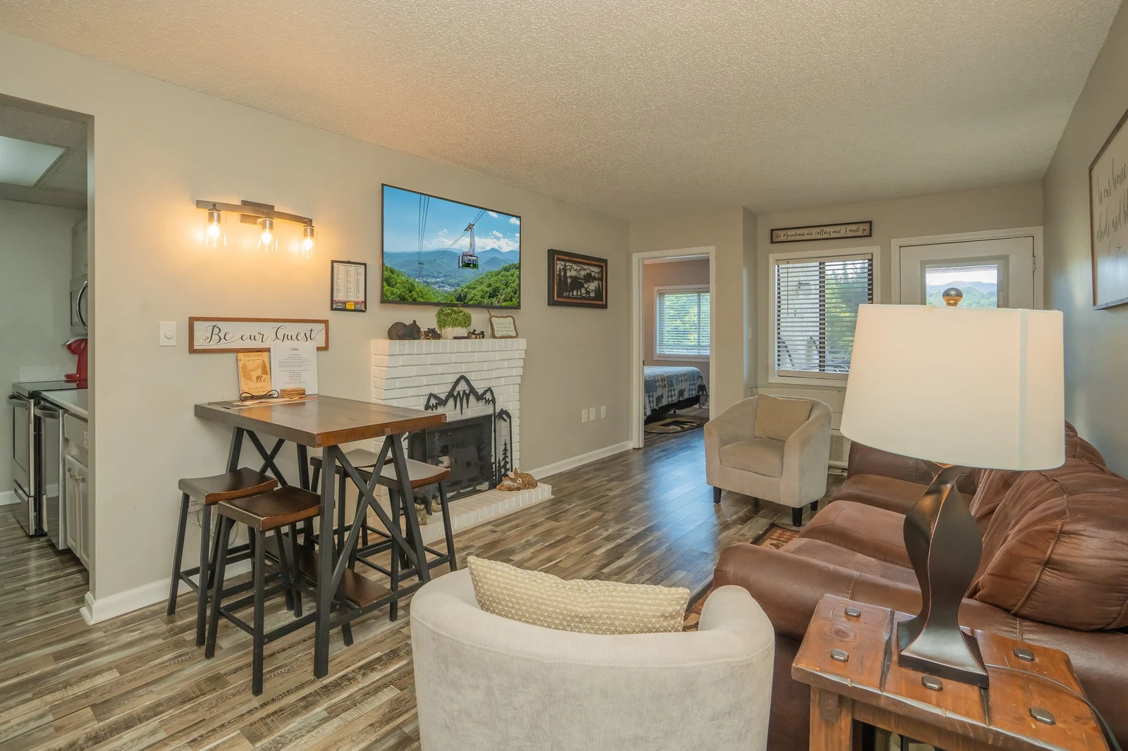 Settle into your bright and inviting open-concept living space, where rustic touches meet modern comfort. Enjoy meals at the cozy high-top table, unwind on the plush leather sofa, and feel right at home in this thoughtfully designed retreat.